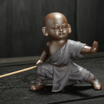 Kung fu-munk som tea pet i violett lera — 1 figur, låg ställning med särade ben, mörkgrå