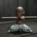 Kung fu-munk som tea pet i violett lera — 1 figur, på huk med händerna ihop, mycket ljusblå