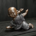 Kung fu-munk som tea pet i violett lera — 1 figur, på knä med båda armarna lyfta, mörkgrå